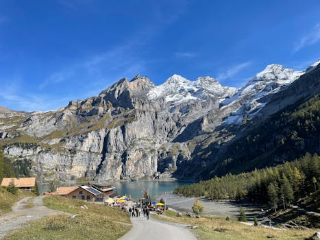 Scenic view of the Swiss Alps with a lake, tourists, and clear blue skies.