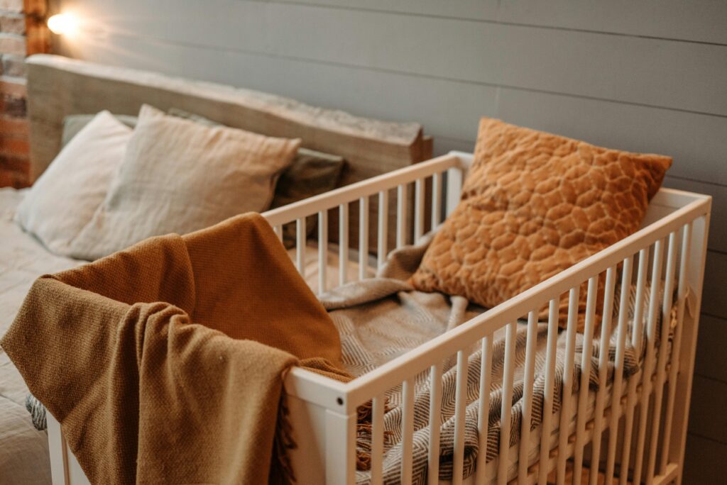 A cozy bedroom featuring a white crib with warm blankets and pillows, creating a comfortable ambiance.